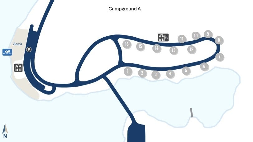 A simple map showing a loop road with numbered locations from 1 to 16 arranged along the outer edges of the loop. A restroom icon is placed near numbers 13, 14, and 15. A beach icon and parking icon appear on the left side of the map near a curved entrance road. Water surrounds much of the loop, and a north arrow is shown in the bottom left corner