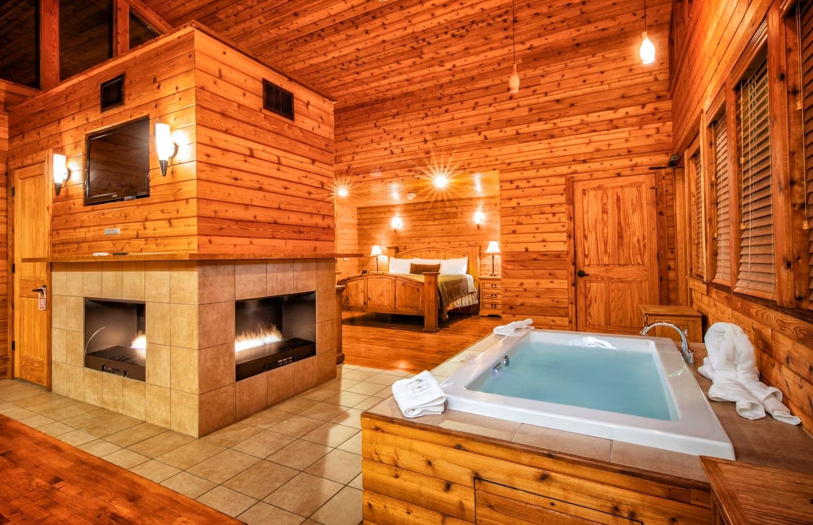 A picture of inside the King Chalet showing an open floor plan with fireplace, Jacuzzi, and bed. 