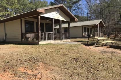 lakeside view of cabins 2 and 3 showing back porch picnic table fire pit and grille