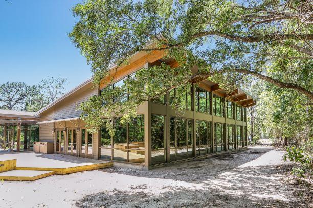 A large building with floor to ceiling windows surrounded by trees.