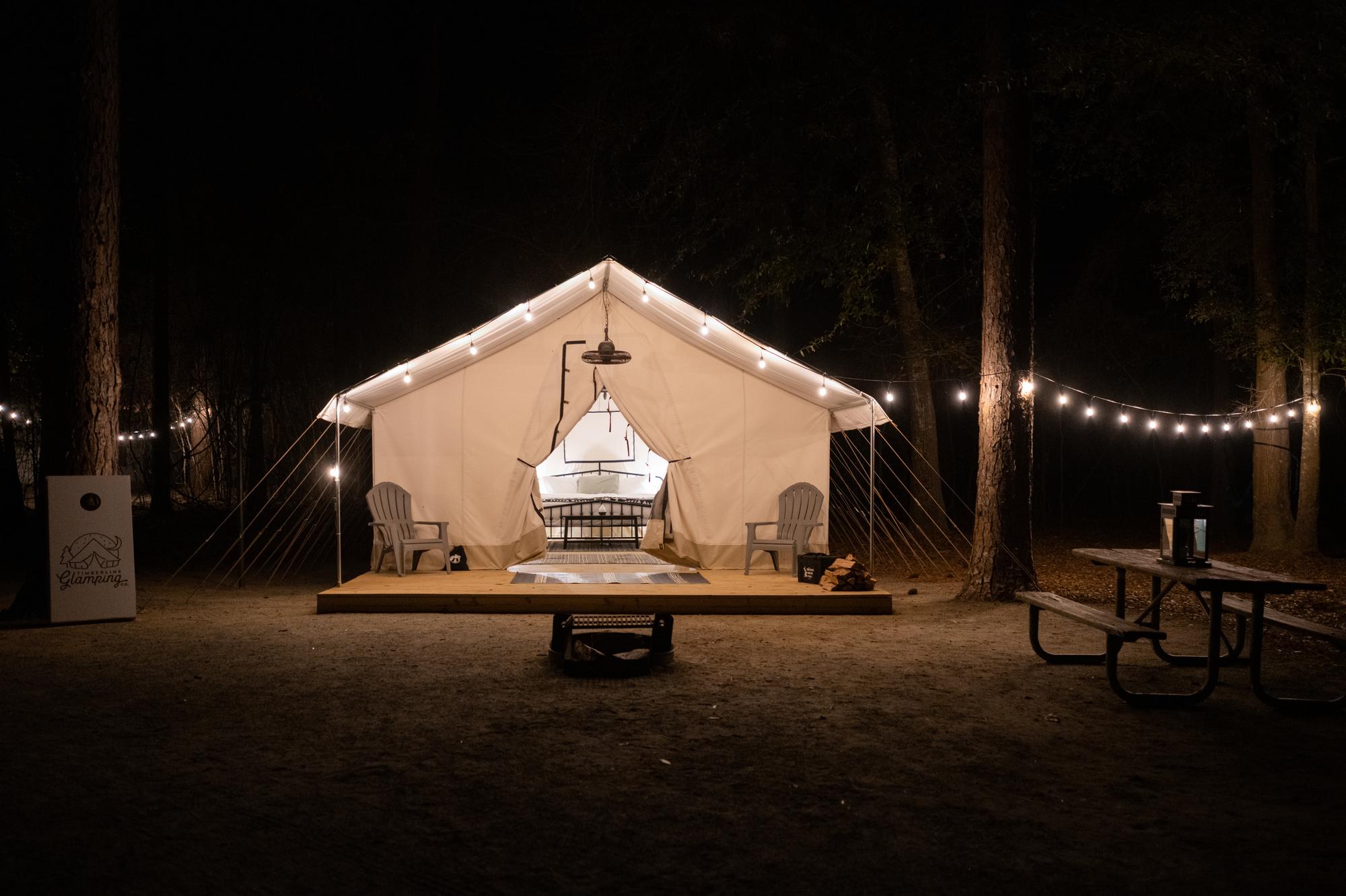 Picture of white tent at night with white lights strung around the outside.